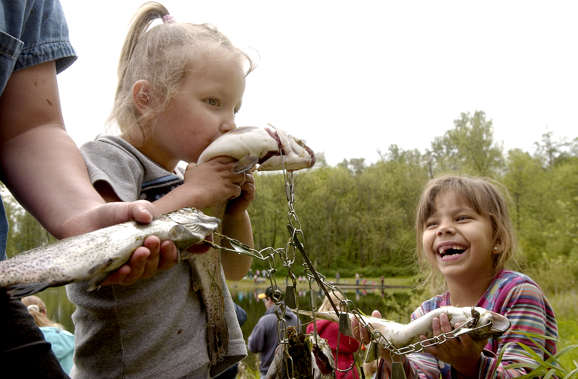 Children gleefully kissing small trout.