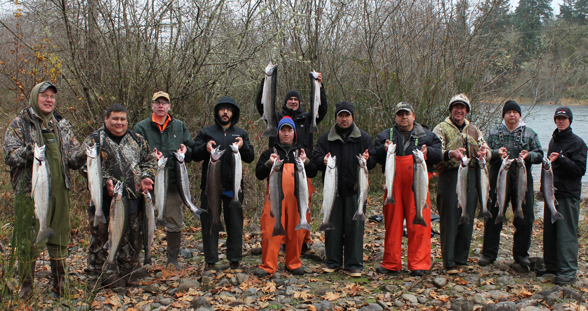 Group of 11 Tribal members each with 2 large salmon they have caught.