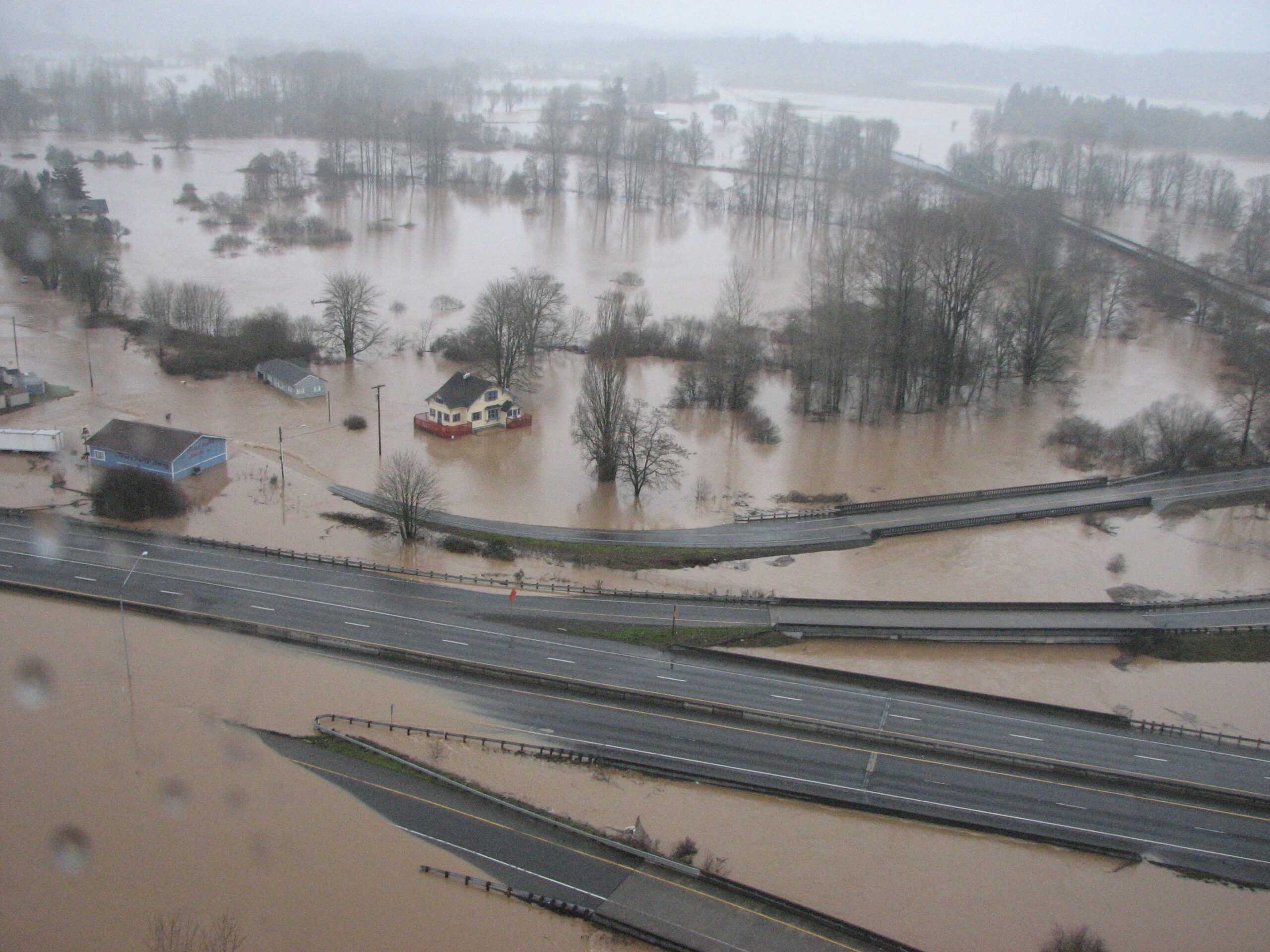 An aerial view of flooding in the Chehalis Basin, with a submerged highway and flooded homes.