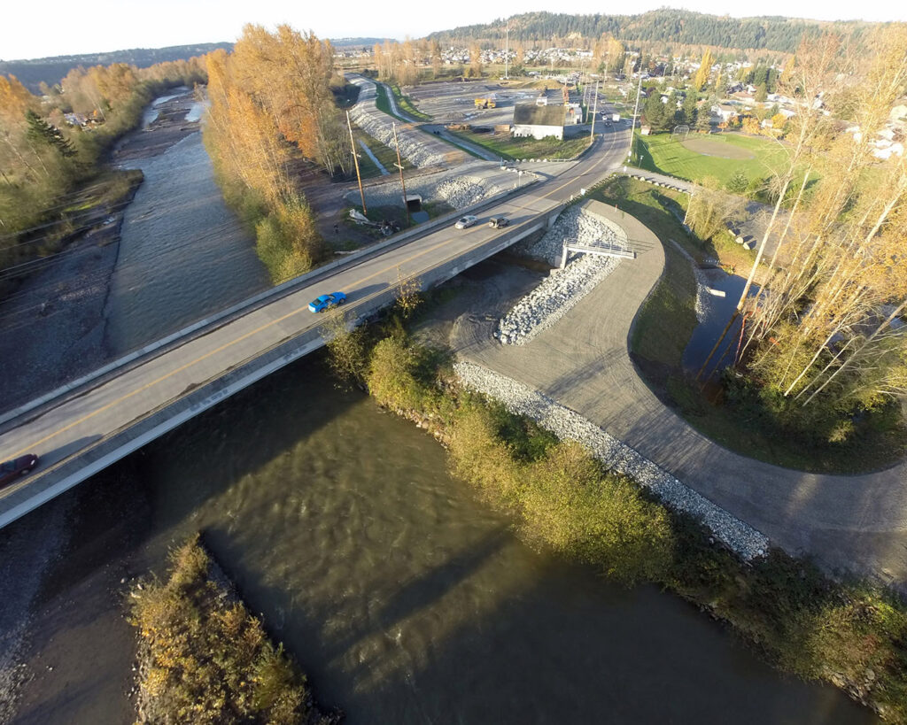 An aerial photograph of a bridge over a meandering section of river with a newly-constructed levee.